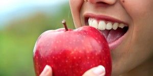 smiling woman biting into a red apple
