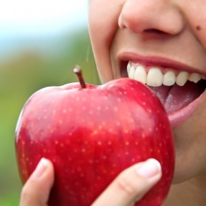 smiling woman biting into a red apple