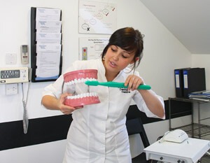 Churchfield Dental Centre team member demonstrating how to brush teeth using a giant replica mouth