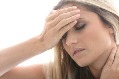 woman holding her hand to her head as if she has a headache